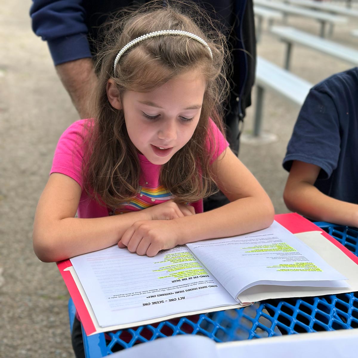 girl reading script at outdoor table